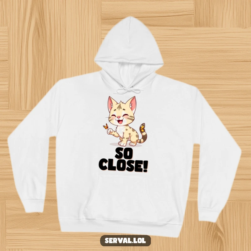 Funny Serval Hoodie: A happy serval character playfully pouncing towards a small butterfly, ideal for cozy, fun wear.